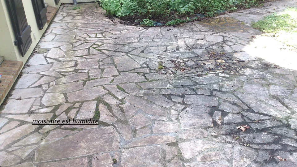 Dallage présentant des traces devant des volets, avec inscription source dans l’image
